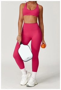 Front view of model in high-waisted fuchsia yoga leggings and sports bra set