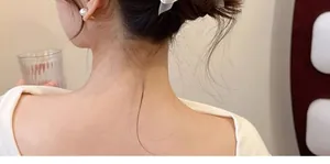 Details von elegantem weißem Chiffon-Haarclip und Perlenohrringen an einem Model