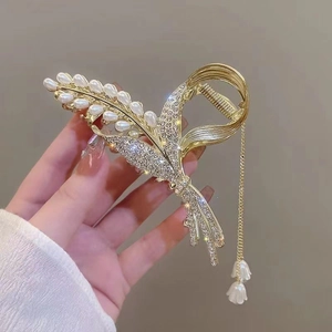 Detail of a gold floral hair claw clip featuring pearls, rhinestones and elegant tassels