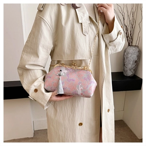 Elegant embroidered evening clutch with tassel and gold chain strap shown in detail