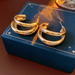 Gros plan de boucles d'oreilles créoles dorées multicouches sur un coffret cadeau