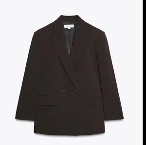 Vue détaillée du blazer croisé marron foncé avec revers cranté et poches à rabat