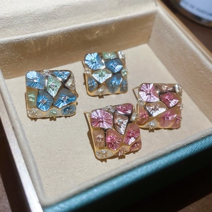 Detail view of gold-plated geometric mosaic flower earrings with enamel and zircon