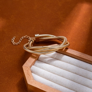 Détail d'un bracelet spirale doré multicouche avec chaîne d'extension sur support bois