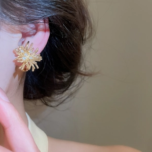Close-up of gold-plated firework ear clip earring with sparkling zircon stones.