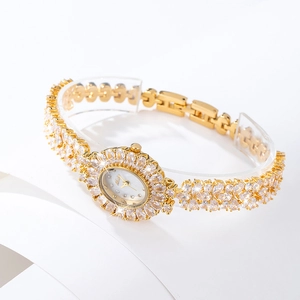 Macro shot of gold-plated women's watch featuring luxury crystal inlay and a white dial