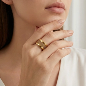 Detail of a wide gold-plated stainless steel ring with mesh texture on female model's hand