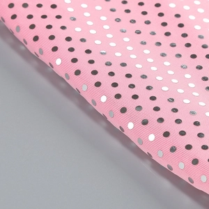 Gros plan détaillé du tissu rose à pois avec paillettes argentées et texture tricot