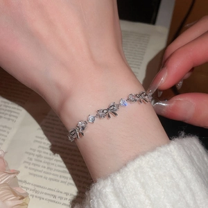 Close-up of sparkling zircon flower bracelet on wrist with elegant silver bow design