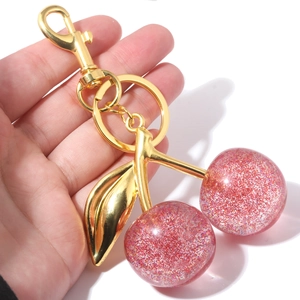 Handheld cherry keychain with pink glitter resin spheres and golden metal hardware