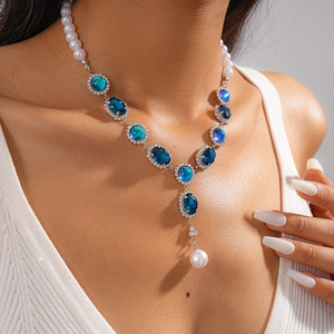 Close-up of vintage necklace with blue gemstones and pearls on model neck