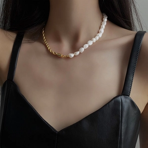 Elegant gold twisted chain and baroque pearl拼接项链 worn by a model in black leather