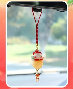 Close-up of a lucky cat car pendant with red rope and golden wealth symbols hanging on a mirror