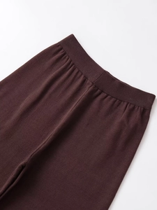 Close-up of dark brown knitted trousers showing elastic waistband and fine fabric texture