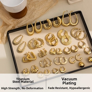 Collection of gold titanium steel C-shaped earrings on a black tray for a luxury display