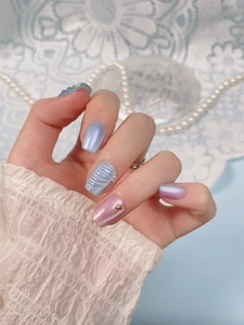 Detail of mermaid style nails with blue-purple cat-eye effect and 3D shell patterns