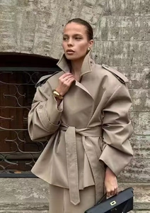 Chic khaki trench coat with adjustable waist belt shown in a stylish outdoor street setting