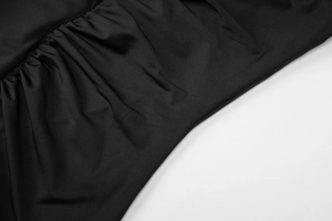 Close-up detail of black ruched fabric texture on a French style bodycon dress