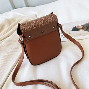 Detail of vintage brown leather crossbody bag with printed feathers and metal rivets