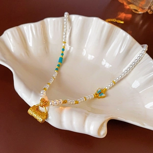 Collier en perles vintage doré 18 carats avec pendentifs papillon et cadenas sur plateau