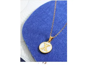 Nahaufnahme der goldenen Kette mit Buchstabe X und weißer Muscheleinlage im Detail