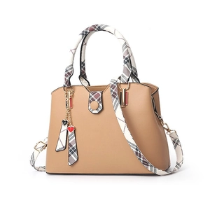 Khaki Handtasche aus Kunstleder mit karierten Riemen und Herzanhänger auf weißem Grund