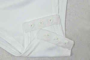 Détail de l'entrejambe d'un body blanc en maille avec trois boutons-pression pratiques