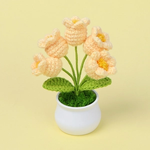 Macro shot of five yellow crocheted lilies in a white pot with detailed knit textures