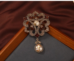 Macro detail of vintage hollow flower brooch with brown gemstones and teardrop pendant