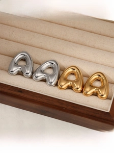 Detailed view of puffed alphabet stud earrings in polished gold and silver finishes