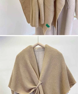 Detail of beige knitted shawl featuring thick ribbed texture and small green tag accent