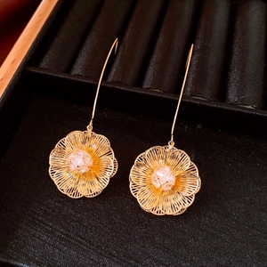 Gros plan détaillé des boucles d'oreilles fleurs plaquées or 18 carats sur un écrin
