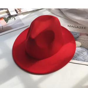 Detail shot of a red wool felt wide-brim jazz fedora hat on a modern white surface