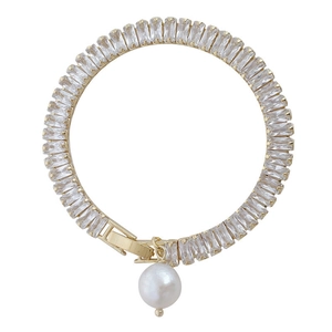Bracelet vintage doré avec pierres de zircon et pendentif perle sur fond blanc