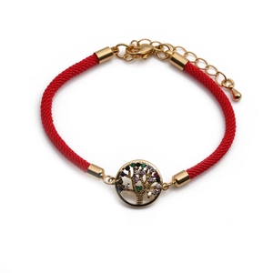 Detail of red woven bracelet with golden tree of life charm and colorful crystals