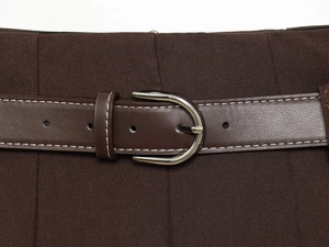 Détail d'une jupe marron foncé avec ceinture en cuir, surpiqûres blanches et boucle en D