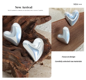 Macro detail of high-shine heart-shaped earrings with metallic mirror finish and minimalist design