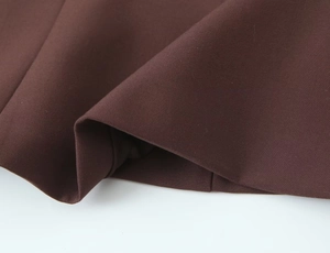 Macro detail of dark brown woven fabric texture and hem stitching on a corset top