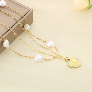 Detail of layered gold necklace with white heart beads and sparkling MOM pendant