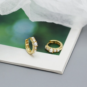 Close-up of golden S925 silver earrings with five pearls set in a minimalist style