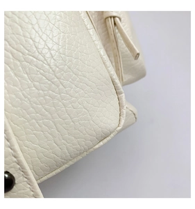 Macro shot of cream lychee grain leather with fine stitching and stud detail on backpack