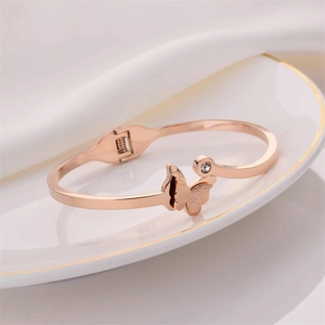 Rose gold open bangle featuring a frosted butterfly charm and sparkling crystal accent