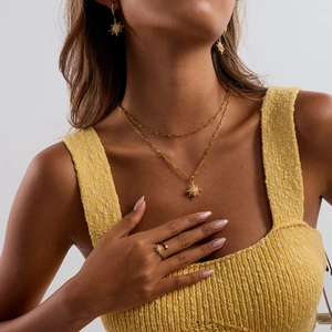 Model trägt goldenes Sonnenstrahl Schmuckset mit Halskette Ohrringen und einem Ring