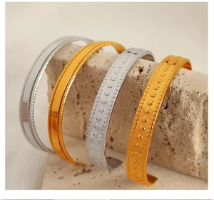 Macro view of textured gold and silver adjustable bangles on stone display stand