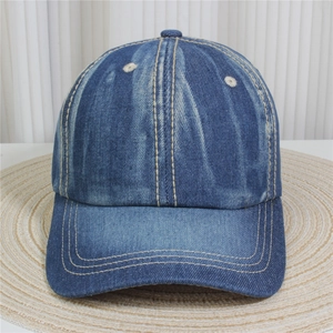 Détail de la casquette de baseball en jean bleu avec strass sur un tapis de paille tressé