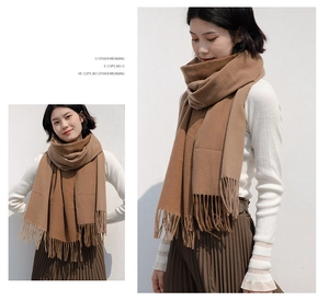 Detailed texture of camel cashmere-feel scarf with neat tassels and soft knit finish