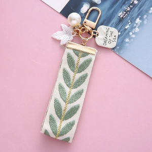 Fresh leaf jacquard ribbon keychain with gold clip and pearl charm on pink background