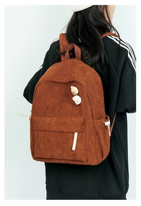 Detail eines braunen Cord-Rucksacks mit Bärenanhängern und seitlichem Kordelzug