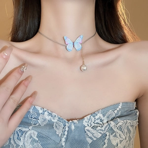 Gros plan d'un élégant collier papillon en acrylique avec détail de perle blanche