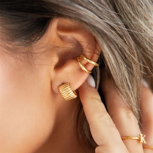 Close-up of gold-plated C-shaped earrings and a K-letter ring on a model